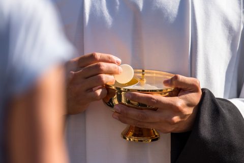 Catholic priest giving beliver a Holy Communion
