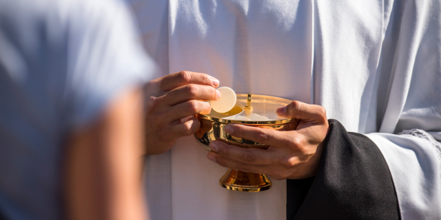 Catholic priest giving beliver a Holy Communion