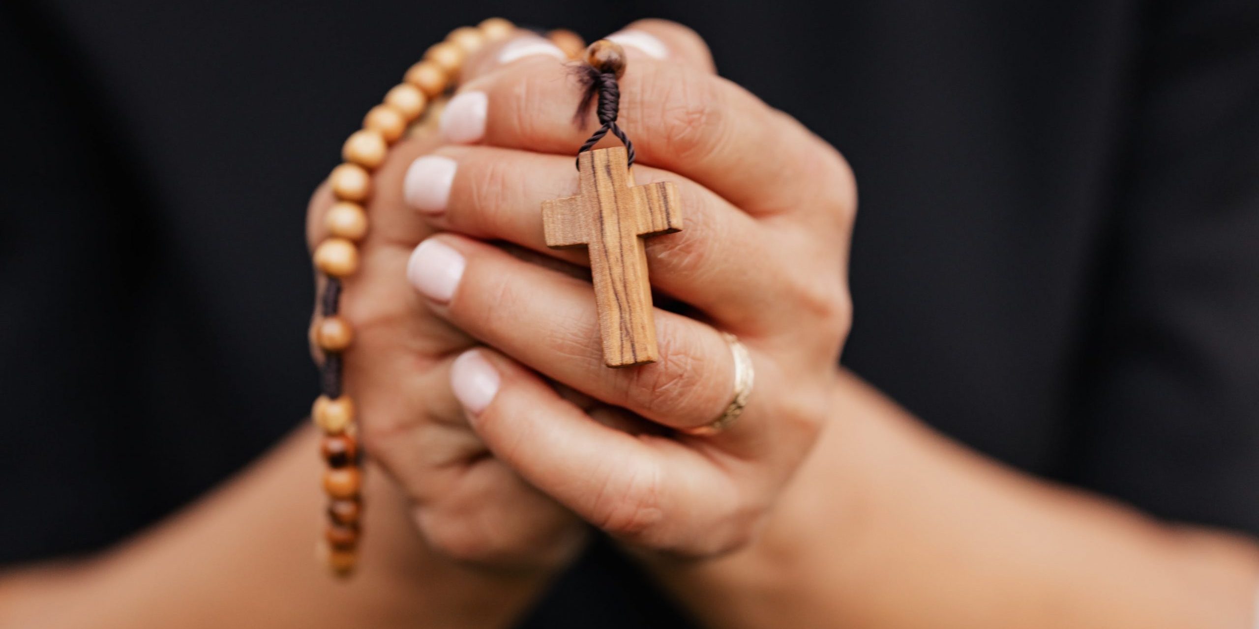 ano-vocacional Mãos femininas segurando um terço de madeira.