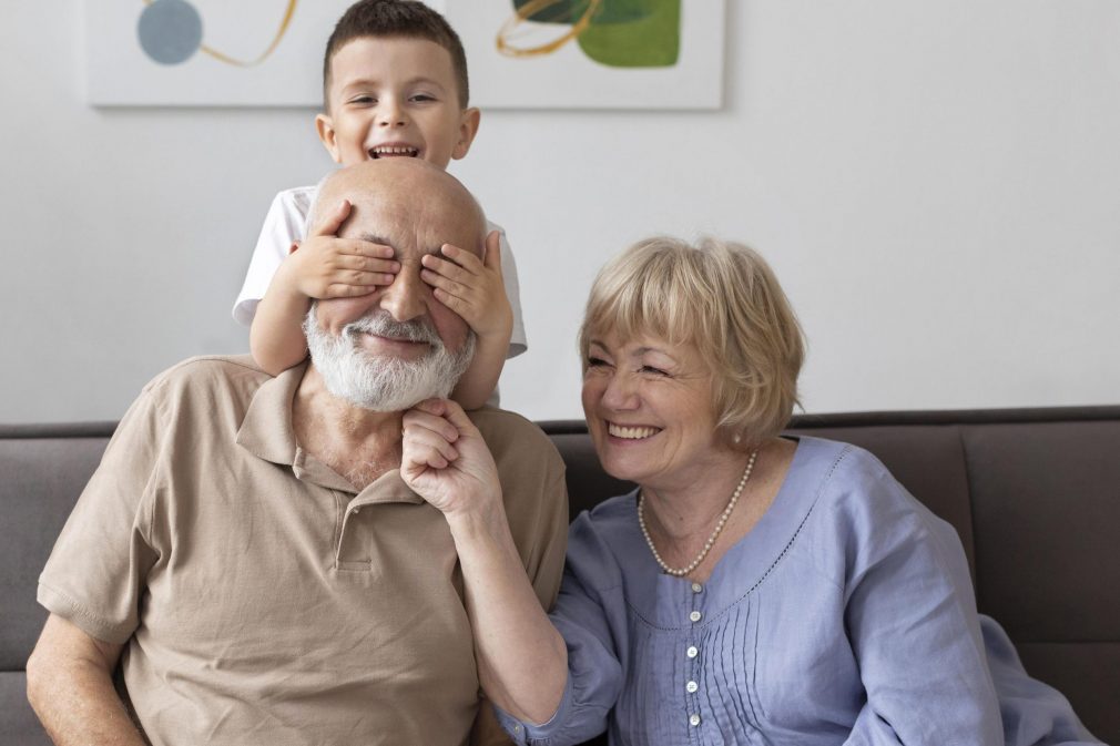full-shot-happy-family-sitting-on-couch (1) Casal de avós e neto.