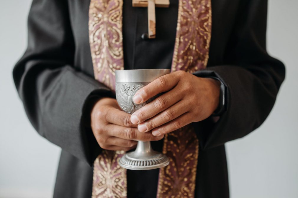padre Padre visto do peito para baixo segurando uma taça de prata.