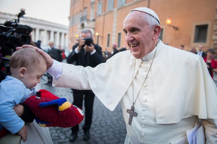 papa-crianca Papa Francisco sorrindo e tocando a cabeça de um bebê.