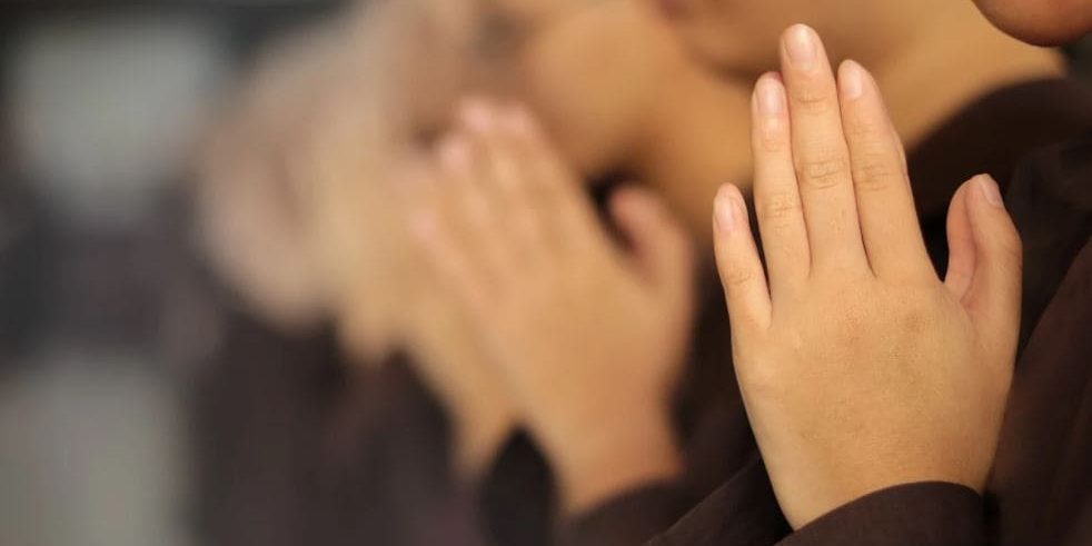 Pessoa com as mãos em gesto de oração